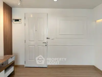 Minimalist interior with white door and wooden flooring, perfect for modern living.