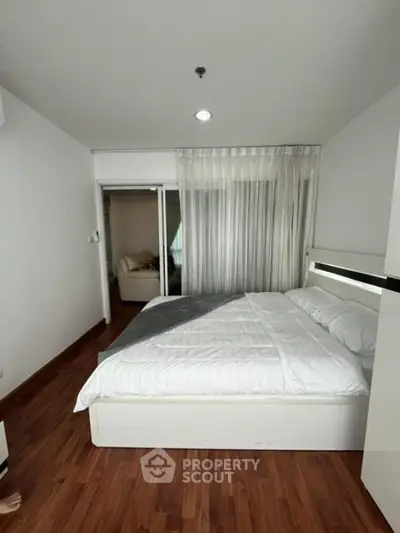 Modern bedroom with wooden flooring and cozy white bedding