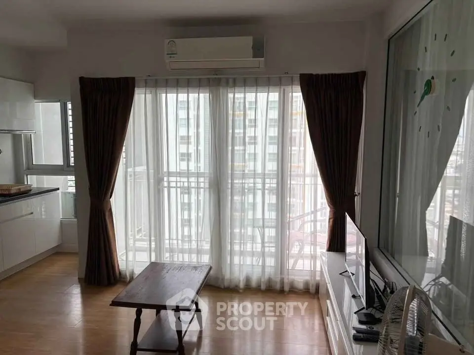 Bright living room with large windows and balcony access in modern apartment.