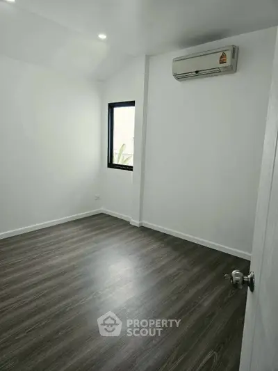 Spacious minimalist bedroom with air conditioning and sleek wooden flooring.