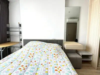 Modern bedroom with stylish decor and ample natural light, featuring a cozy bed and functional furniture.