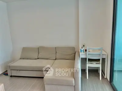 Modern living room with cozy beige sofa and compact study desk near glass door.