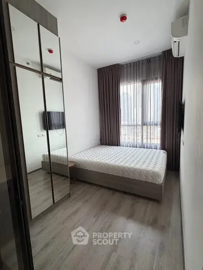 Modern bedroom with large window and mirrored wardrobe in a stylish apartment.