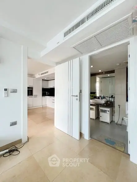 Spacious modern kitchen with open layout and adjacent bathroom in luxury apartment.