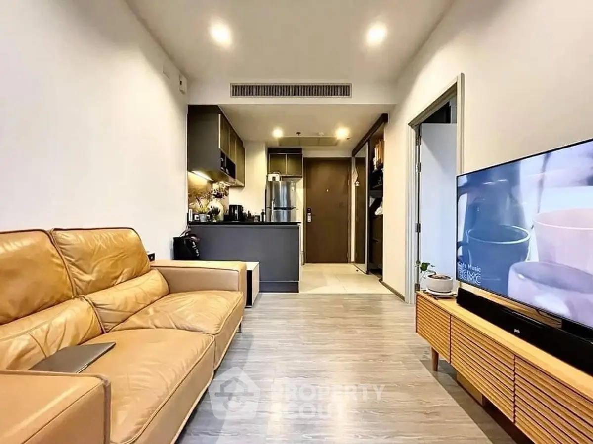 Modern living room with leather sofa and sleek kitchen in open layout apartment.