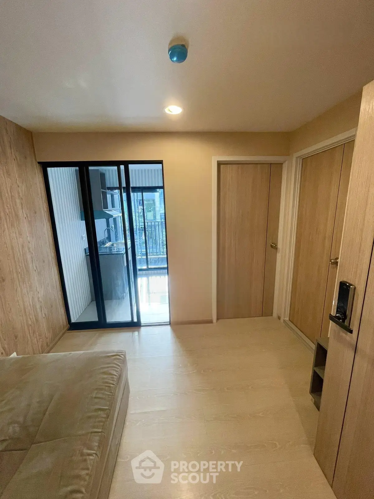 Modern bedroom with wooden flooring and balcony access in a stylish apartment.