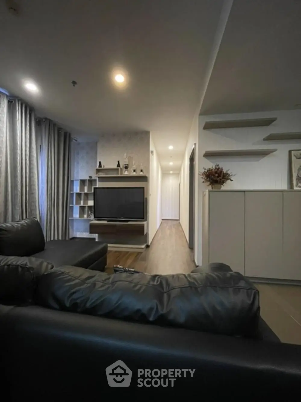Modern living room with sleek black leather sofa and wall-mounted TV