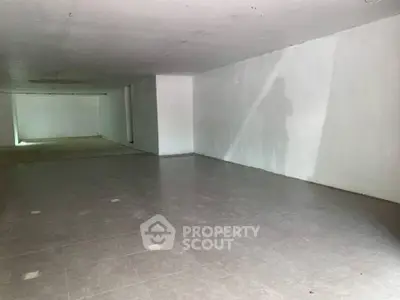 Spacious unfinished basement with tiled flooring and white walls, ideal for customization.