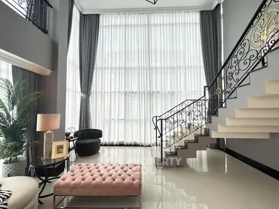 Luxurious living room with high ceilings, elegant staircase, and chic decor in a modern home.