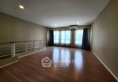 Spacious empty living room with wooden flooring and large windows