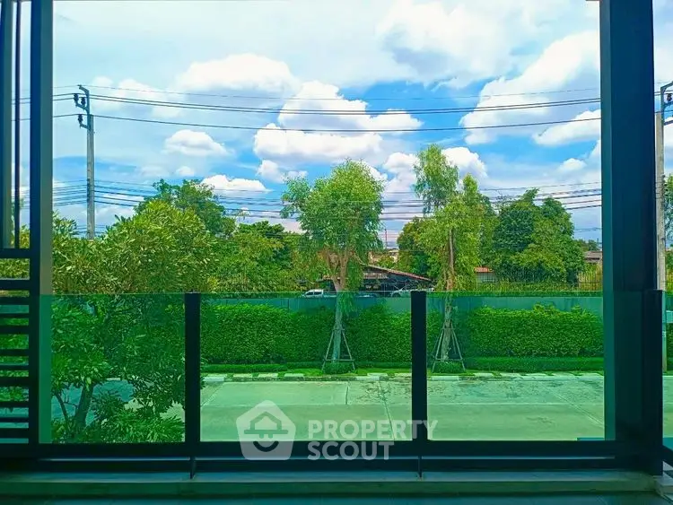 Stunning garden view from modern balcony with lush greenery and clear blue sky.