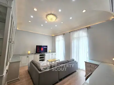 Elegant living room with modern decor and ample natural light, featuring a stylish ceiling light and comfortable seating.