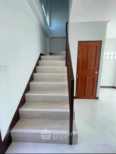 Modern staircase with wooden railing in a bright interior space