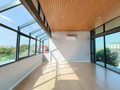 Spacious sunlit room with large windows and wooden ceiling, perfect for modern living.