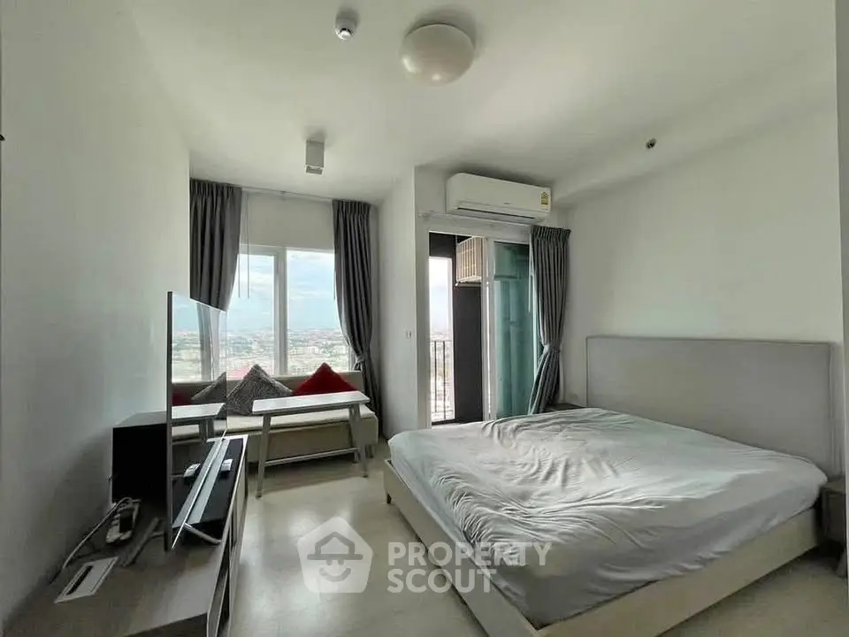 Modern bedroom with balcony and city view, featuring sleek furniture and ample natural light.