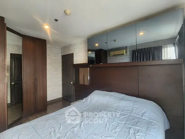 Spacious bedroom with modern wooden furniture and mirrored wardrobe in a stylish apartment.