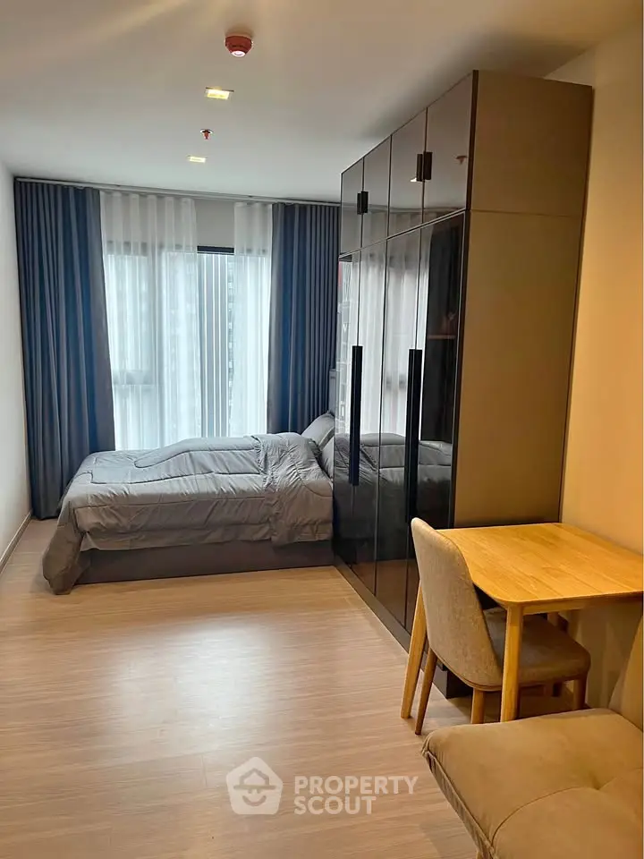 Modern bedroom with sleek wardrobe and cozy workspace in stylish apartment.