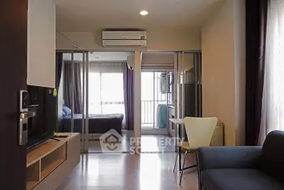 Modern apartment interior with open living room and bedroom view, featuring sleek furniture and natural light.
