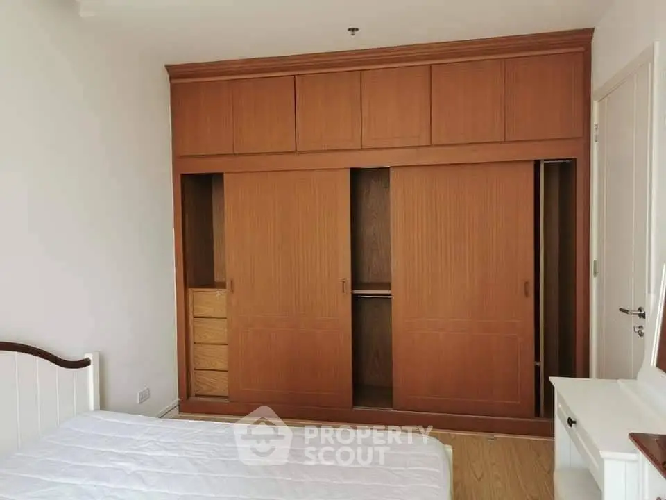 Spacious bedroom with built-in wooden wardrobe and cozy bed setup