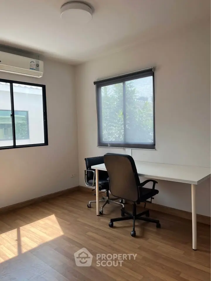 Bright study room with wooden flooring and modern furniture, ideal for productivity.