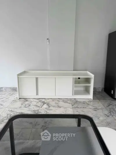 Modern minimalist living room with sleek white furniture and marble flooring.