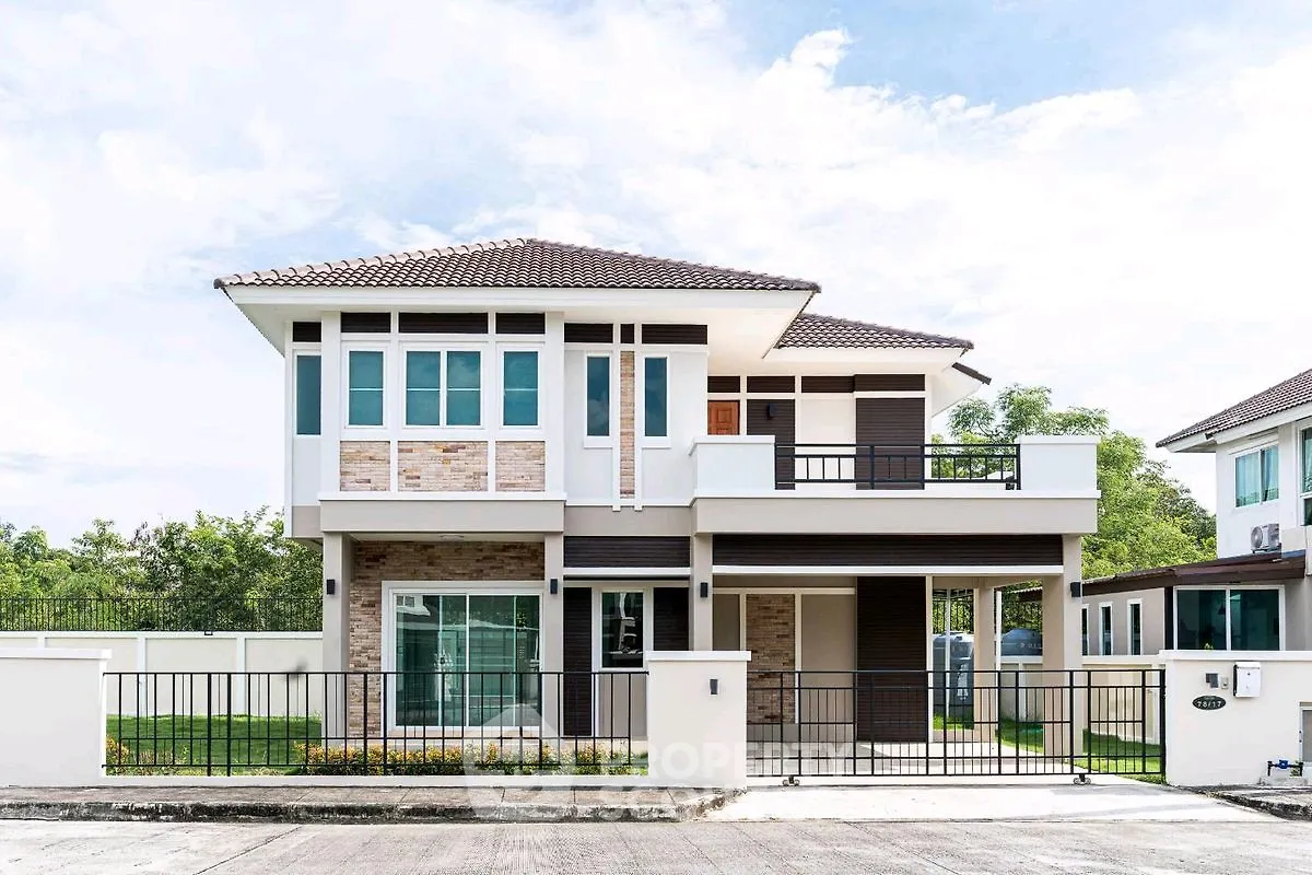 Modern two-story house with balcony and gated entrance in suburban neighborhood.