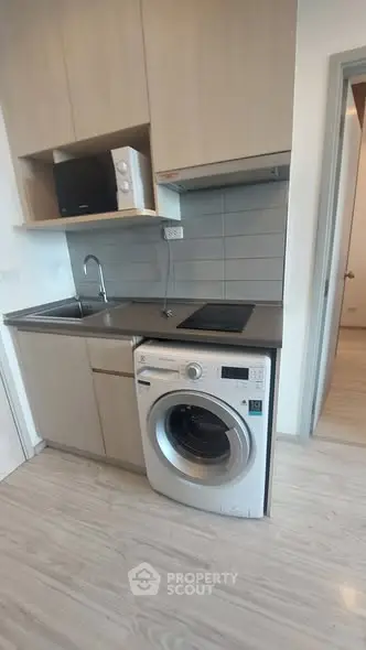 Modern kitchen with washing machine and microwave in compact layout