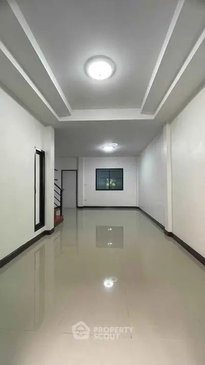 Spacious empty room with glossy tiled floor and modern ceiling lights, ideal for customization.