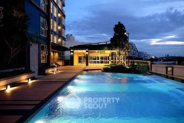 Luxurious condominium with illuminated pool and modern architecture at dusk.