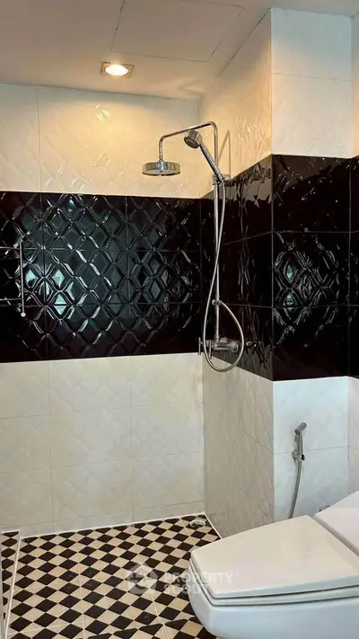 Modern bathroom with stylish black and white tiles and sleek shower design.