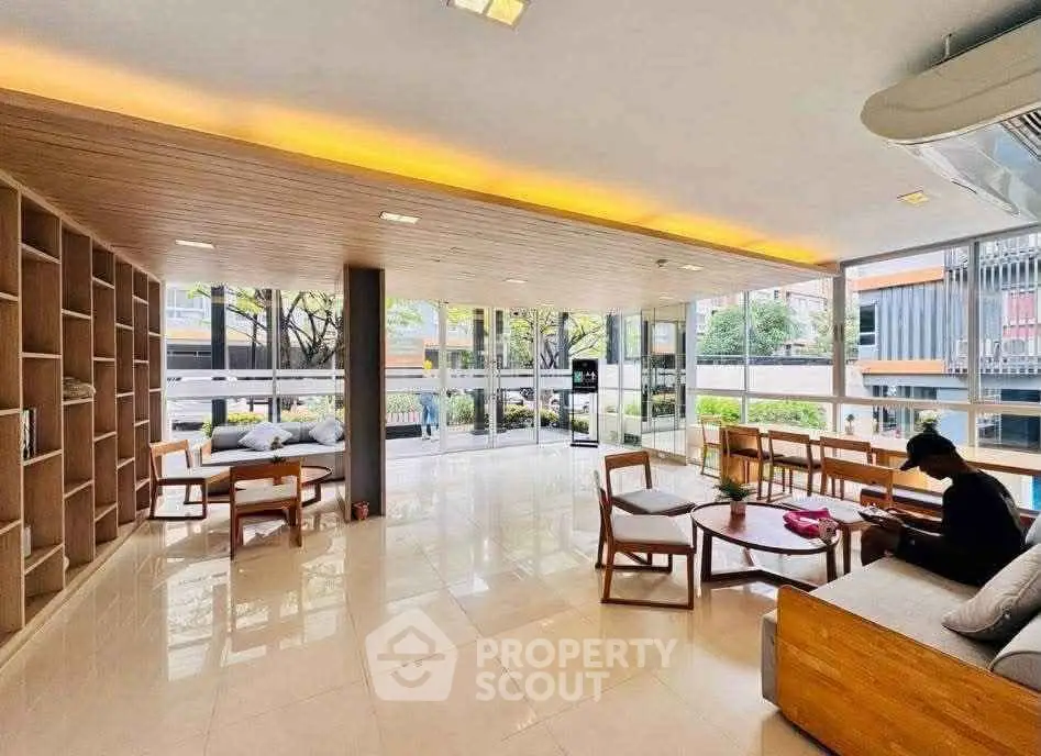 Spacious modern living room with large windows and natural light, featuring stylish furniture and open layout.