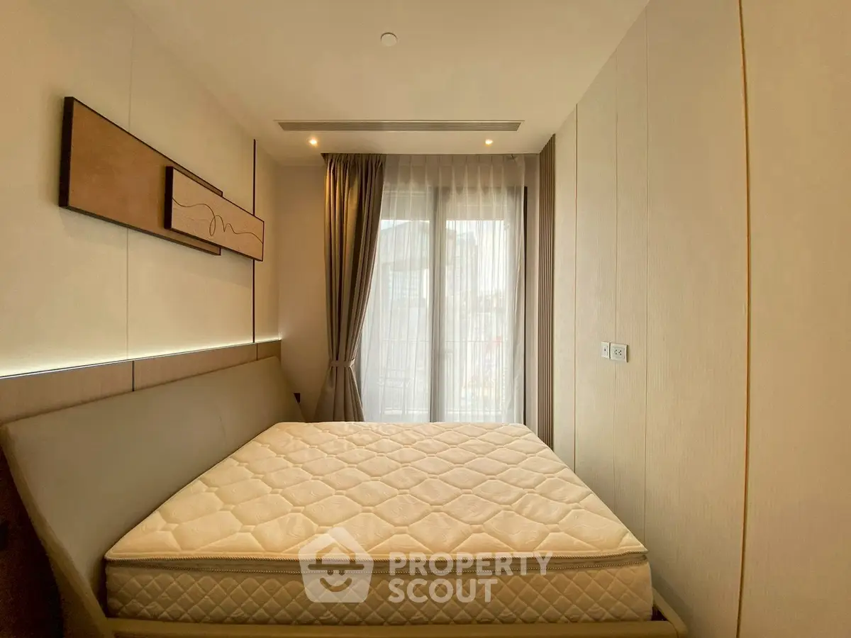 Modern bedroom with large window and stylish decor in a contemporary apartment.