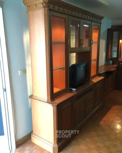 Elegant wooden entertainment center with glass cabinets and TV in a cozy living room setting.