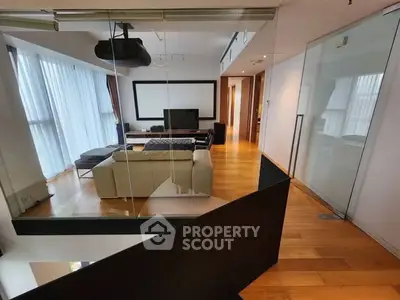 Spacious modern living room with projector and large screen, featuring sleek design and abundant natural light.