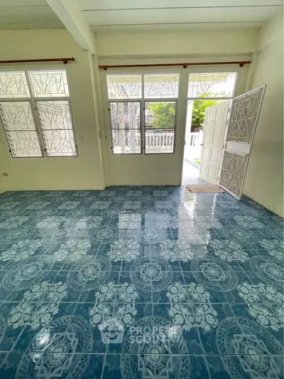 Spacious room with decorative blue tiled floor and large windows for natural light.