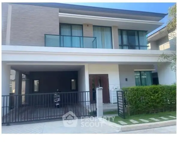Modern two-story house with gated driveway and lush greenery