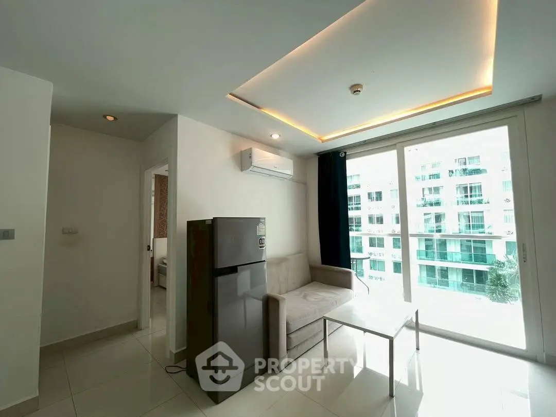 Modern living room with sleek design and natural light, featuring a compact sofa and refrigerator.
