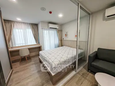 Modern bedroom with stylish decor and natural light, featuring a cozy bed and workspace.