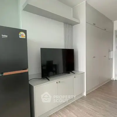 Modern apartment interior with sleek TV unit and refrigerator, showcasing minimalist design.