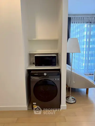 Modern apartment interior with washing machine and microwave in cozy living space.