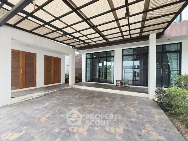Modern home entrance with stylish glass doors and spacious tiled patio.