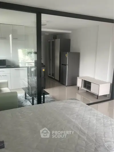 Modern studio apartment with sleek kitchen and open layout, featuring a cozy living area and contemporary furnishings.