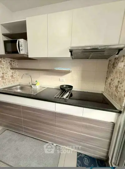 Modern kitchen with sleek cabinetry and built-in microwave, featuring a stylish backsplash.