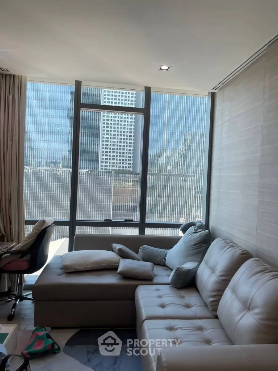 Modern living room with large windows and city view, featuring a stylish sofa and contemporary decor.