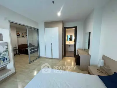 Modern bedroom with sliding glass doors and ensuite bathroom in a stylish apartment.