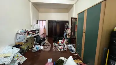 Cluttered bedroom with wardrobes and scattered belongings, potential for renovation.