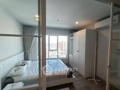 Modern bedroom with large window and city view, featuring sleek furniture and natural light.