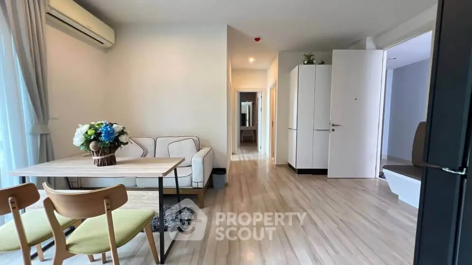 Modern living room with wooden flooring and cozy dining area in a stylish apartment.