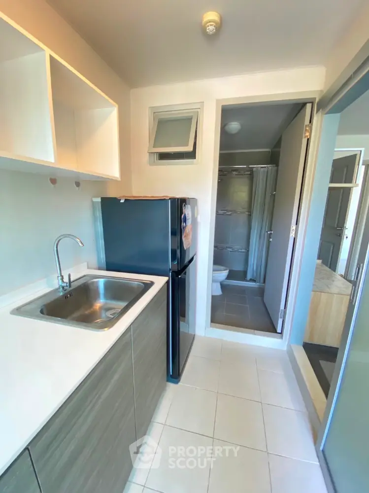 Compact kitchen with modern appliances leading to a small bathroom, ideal for urban living.