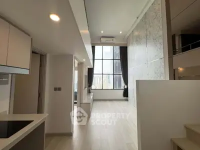 Modern loft apartment with high ceilings and large windows offering city views, featuring sleek kitchen design.